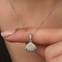 Silver shell pendant necklace held by a hand