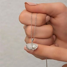 Hand holding a silver necklace with a butterfly pendant against a neutral background