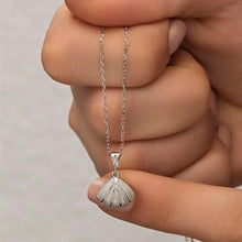 Silver necklace with a fan-shaped pendant held between fingers against a neutral background