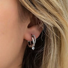 Close-up of an ear wearing a silver hoop earring with a blurred background