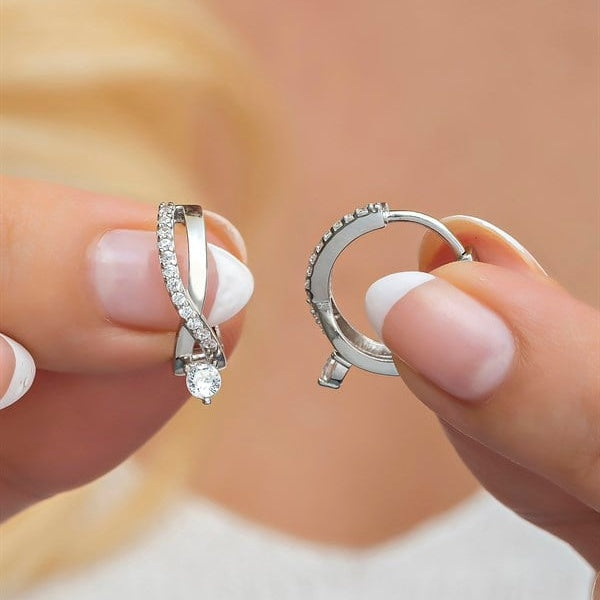 Two diamond rings held between fingers against a blurred background