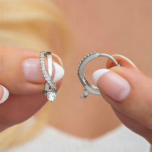 Two diamond rings held between fingers against a blurred background