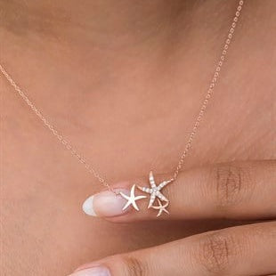 Rose gold starfish necklace on a person's neck with a blurred background