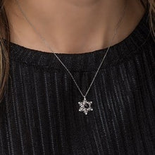 Snowflake pendant necklace on a person wearing a black outfit