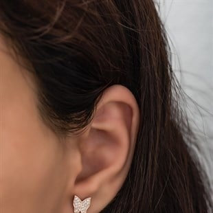 Close-up of an ear wearing a diamond earring with a blurred background