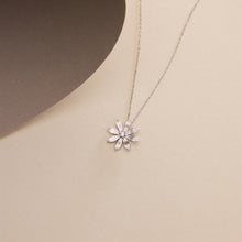 Silver flower-shaped pendant necklace on a beige background