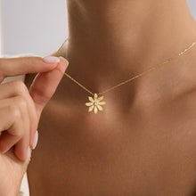 Gold necklace with a flower pendant being worn on a person's neck.