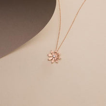 Rose gold flower-shaped necklace on a beige background