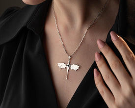 Silver necklace with a unique pendant worn by a person against a dark background