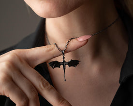 Person wearing a black bat-shaped pendant necklace