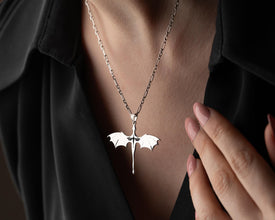 Silver bat-shaped pendant necklace on a person wearing a black shirt.