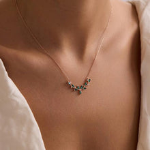 Necklace with green gemstones worn by a person, close-up on skin