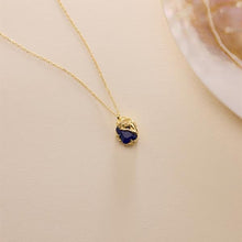 Gold necklace with a blue pendant on a beige background