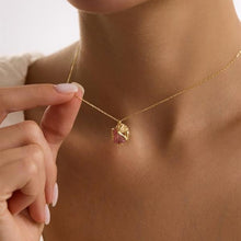 Gold necklace with a pink gemstone pendant being worn.
