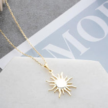 Gold sun-shaped pendant necklace on a magazine background