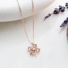 Rose gold necklace with a floral pendant on a white surface with lavender flowers.