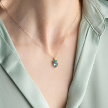 Necklace with a heart-shaped pendant worn by a person in a light green outfit.