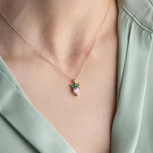 Necklace with a strawberry pendant worn by a person in a light green top.