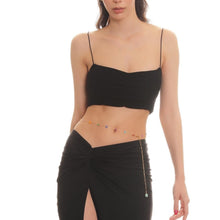 Woman wearing a black crop top and black skirt on a white background