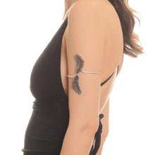 Woman wearing a black dress with a feather arm accessory on a white background