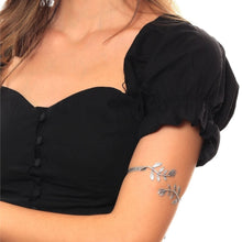 Person wearing a black top with a floral arm bandage on a white background