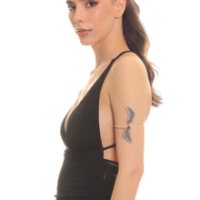 Woman wearing a black sleeveless top with decorative arm piece on a white background