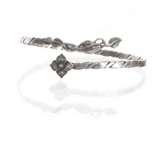 Silver bracelet with floral design on a white background