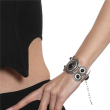 Close-up of a wrist wearing a decorative bracelet with black stones on a white background