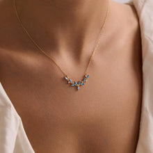 Gold necklace with blue stones on a person wearing a white shirt