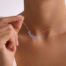 Rose gold necklace with blue stones being worn on a person's neck