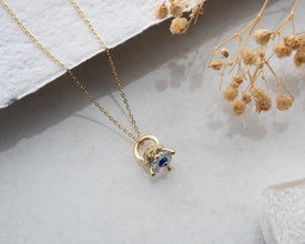 Close-up of a protective blue crystal necklace, highlighting the intricate claw-shaped silver setting.
