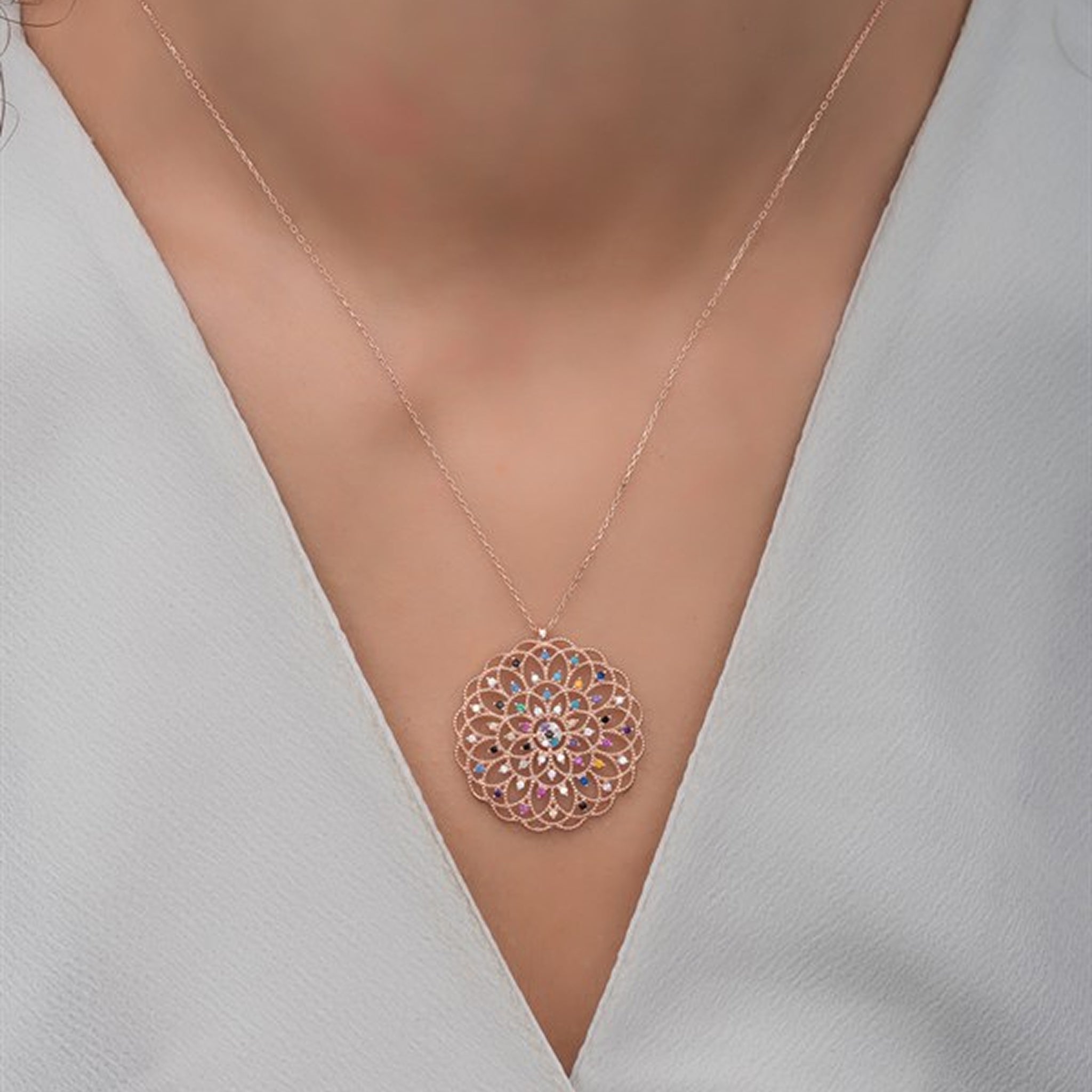 Rose gold necklace with a intricate pendant on a model wearing a white top