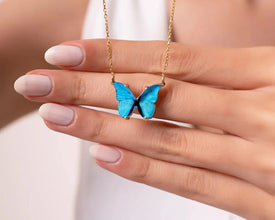 Close-up of a sterling silver butterfly necklace with a blue gemstone accent.