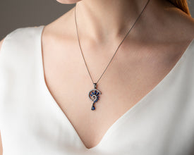 Luxury unboxing: blue crystal pendant emerging from velvet coffin box