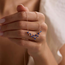 Necklace with blue stones held by a hand against a neutral background
