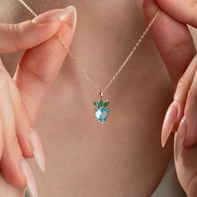 Heart-shaped blue gemstone necklace held by hands with a neutral background