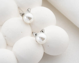 Cat-shaped earrings with pearl-like finish on a white background