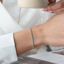 Close-up of a wrist wearing a blue beaded bracelet with a blurred background