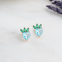 Heart-shaped earrings with green and blue stones on a light background