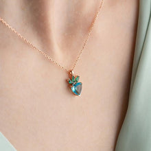 Necklace with a heart-shaped green gemstone pendant on a person's neck.