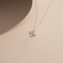 Silver flower-shaped pendant necklace on a beige background