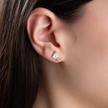 Close-up of an ear wearing a floral earring with a blurred background