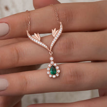 Rose gold necklace with emerald and diamond pendant on a hand
