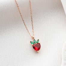 Heart-shaped red gemstone necklace with green accents on a white background