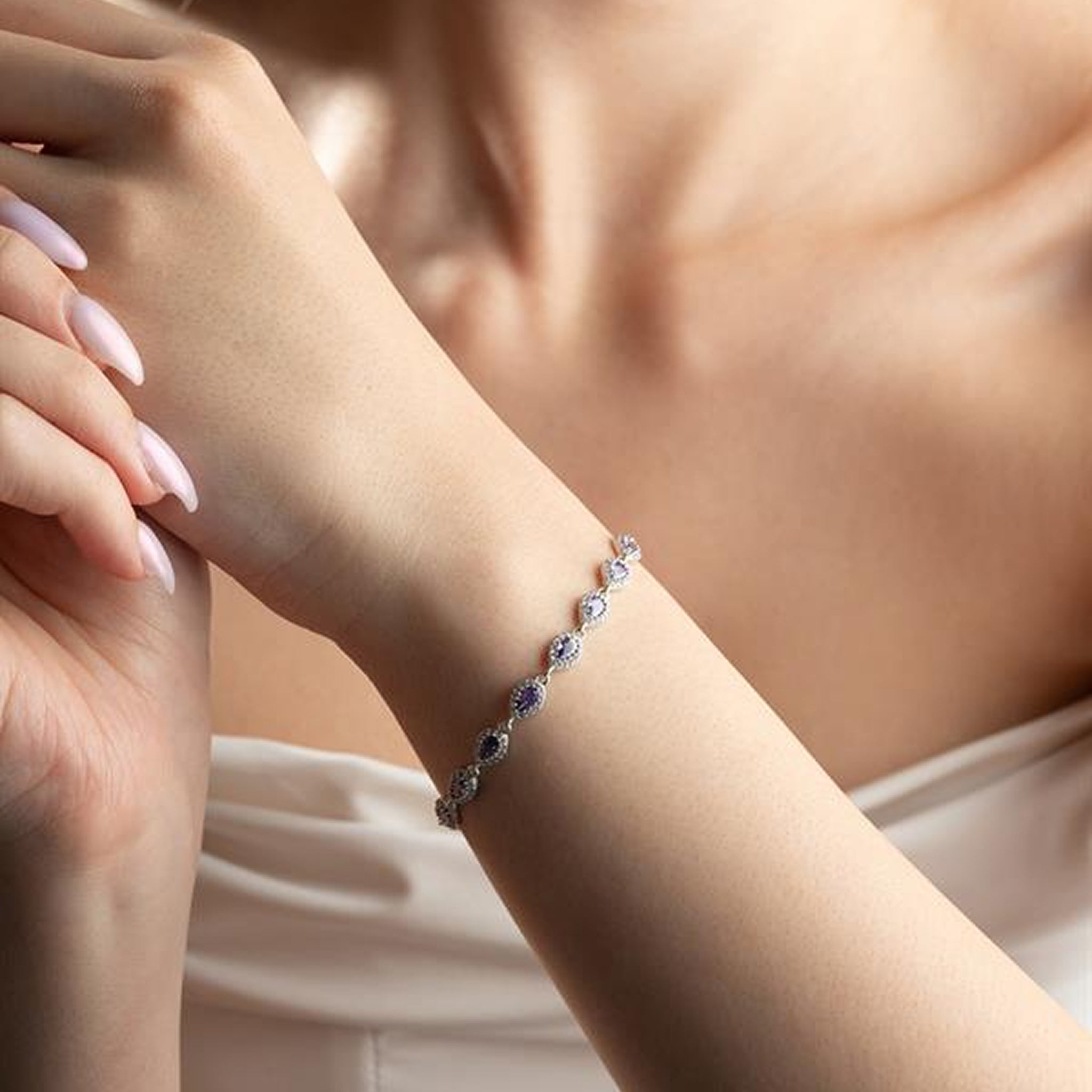 Close-up of a hand wearing a delicate bracelet with small stones.