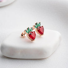 Pair of earrings with red and green gemstones on a white stone surface