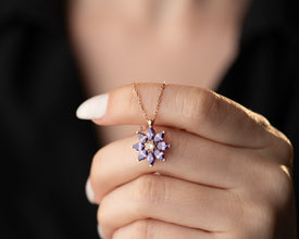 Vintage-style silver flower pendant with purple gemstone details.