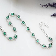 Silver necklace with green gemstones on a white background