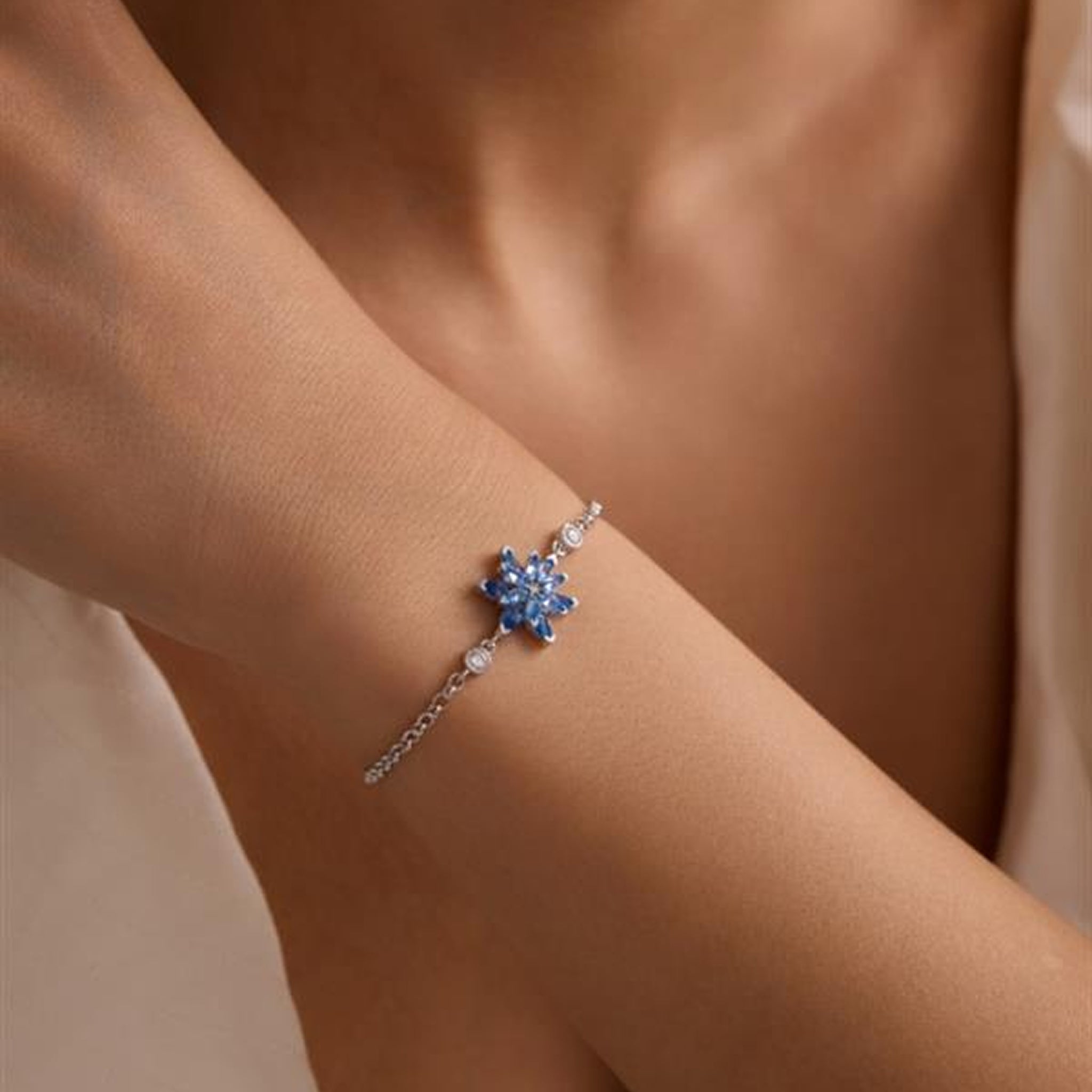 Silver bracelet with a blue gemstone on a wrist against a neutral background