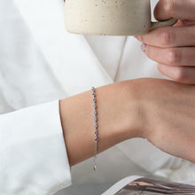 Person holding a mug with a bracelet on a plain background